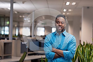 Portrait of confident young african american businessman with arms crossed standing at workplace