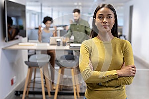 Portrait of confident young african american female advisor standing with arms crossed at workplace