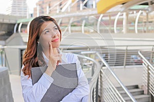 Portrait of confident young Asian businesswoman feeling happy and looking far away in the city building background. Creative busin