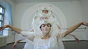 Portrait of confident young beautiful woman moving in slow motion with friends dancing in white costume. Talented