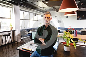 Portrait of confident young caucasian businessman with arms crossed in creative office photo