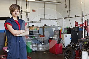 Portrait of a confident young female mechanic with arms crossed in garage