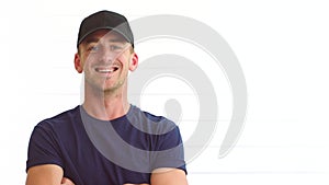 Portrait of a confident young man smiling and laughing against a white background while standing with arms crossed