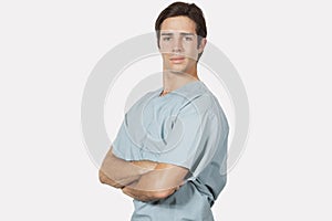 Portrait of confident young man in surgical scrubs standing against gray background