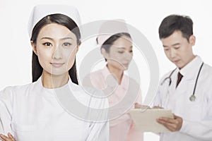 Portrait of confident young nurse, doctor and nurse in the background, studio shot