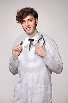 Portrait of confident young smiling medical doctor with sthetoscope over light gray background