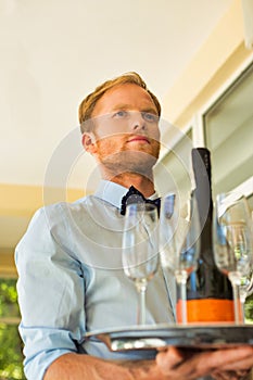 Portrait of confident young waiter serving wine at restaurant
