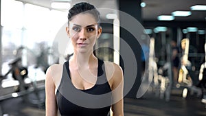 Portrait of confident young woman in gym looking into camera, personal trainer