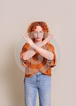 Portrait of confident young woman showing rejecting sign with crossed hands over white background