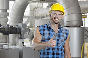 Portrait of confident young worker gesturing thumbs up in industry