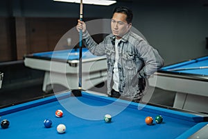 portrait of confuse pool player put his hand on his waist