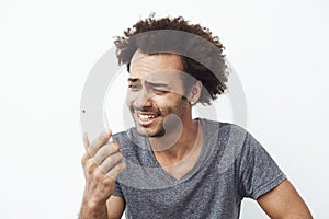 Portrait of confused but cheerful and handsome african man smiling looking at cell phone surprised with a photo on