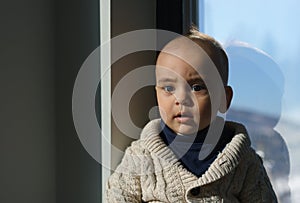 Portrait of a Confused face kid sitting beside the window