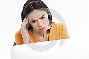 Portrait of confused hotline assistant woman wearing microphone headset speaking with customer by phone in office