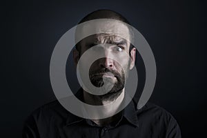 Portrait of confused man on black background.