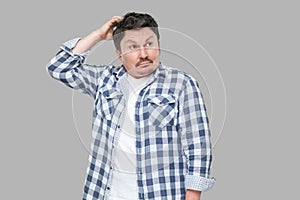 Portrait of confused or thoughtful handsome middle aged business man in casual checkered shirt standing touching his head and