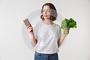 Portrait of a confused young woman holding chocolate bar