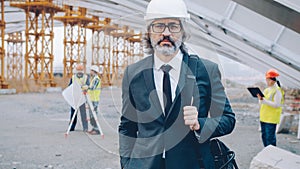 portrait of construction project manager standing outdoors wearing helmet and suit