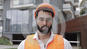 Portrait of construction worker on building site looking at the camera. The builder stands against the backdrop of a