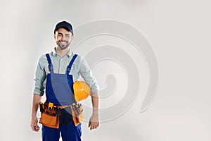 Portrait of construction worker with hard hat and tool belt on light background