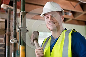 Portrait Of Construction Worker With Sledgehammer Demolishing Wall In Renovated House photo