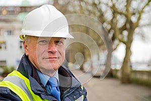 Portrait of construction worker wearing white safety helmet and high visibility vest.