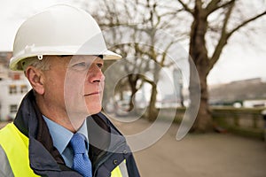 Portrait of construction worker wearing white safety helmet and high visibility vest.