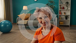 Portrait of a contented smiling elderly woman in the living room close up. A grayhaired retired woman, tired, but