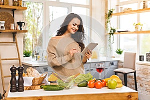 Portrait of cooking healthy food young woman in kitchen looking for a recipe on the Internet. Using tablet computer