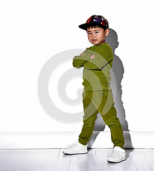 Portrait of a cool asian boy in a cap and green suit standing on a white background.