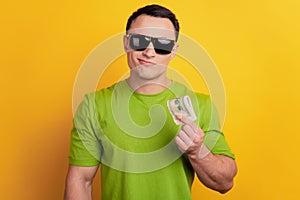 Portrait of cool confident wealthy guy hold dollar banknote on yellow background