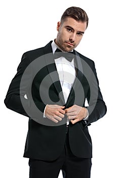 Portrait of cool fashion man buttoning black tuxedo