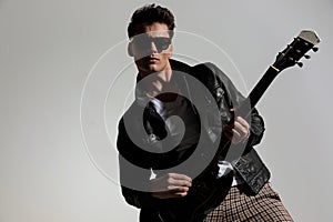 cool guitarist with leather jacket and sunglasses playing guitar