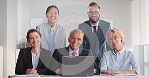 Portrait of corporate business team working on laptop and smiling at camera