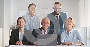 Portrait of corporate business team working on laptop and smiling at camera