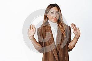Portrait of corporate woman raising hands up, looking clueless and innocent, being uninvolved, dont know, standing over