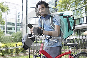 Portrait Of Corurier On Bike Delivering Takeaway Food Using Mobile Phone