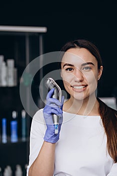 portrait of a cosmetologist with a dermapen device photo