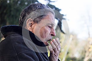 Portrait of a coughing senior man outdoors