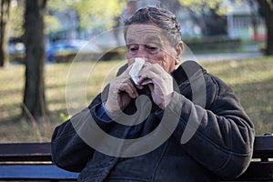 Portrait of a coughing senior man outdoors, looking down