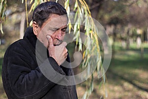 Portrait of a coughing senior man outdoors