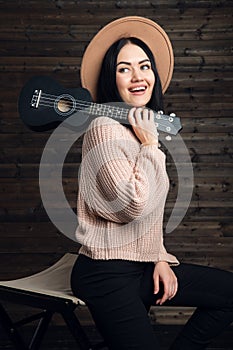 Portrait of country style girl posing with her small guitar on a chair