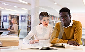Portrait of couple of adult students studying together in public library