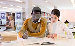 Portrait of couple of adult students studying together in public library