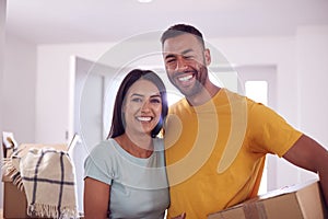 Portrait Of Couple Carrying Boxes Through Front Door Of New Home On Moving Day