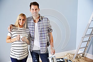 Portrait Of Couple Decorating Nursery For New Baby