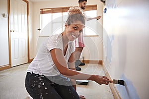 Portrait Of Couple Decorating Room In New Home Painting Wall Together