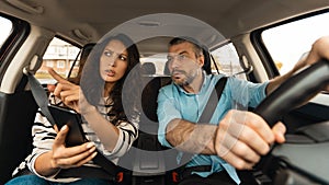 Portrait of couple driving car and using cell phone