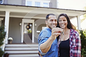 Portrait Of Couple Holding Keys To New Home On Moving In Day