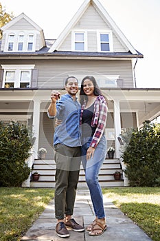 Portrait Of Couple Holding Keys To New Home On Moving In Day